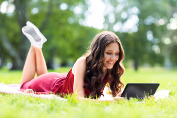 leisure, technology and people concept - happy smiling woman with tablet computer lying on picnic...