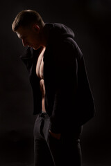 Fototapeta na wymiar Bodybuilder standing in black hoodie. Studio shot. Isolated