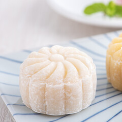 Colorful snow skin moon cake, sweet snowy mooncake, traditional savory dessert for Mid-Autumn Festival on bright wooden background, close up, lifestyle.