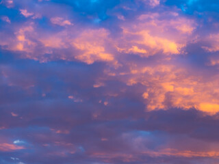 A colorful sky full of pink, blue and orange colors. Contrasting clouds shimmering in different colors at sunset, illuminated by the setting sun. Bright saturated natural background.