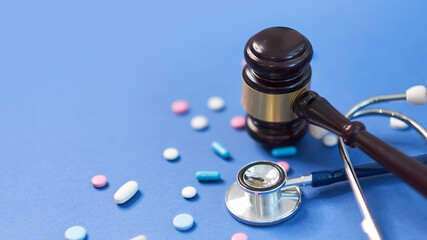Wooden judge gavel with drugs on table. Space for text. Medical concept. on a blue background. expired drugs. fake market.