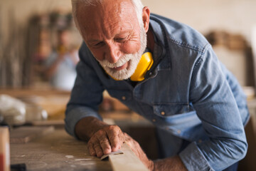 Close up of cheerful dedicated carpenter using sandpaper - obrazy, fototapety, plakaty