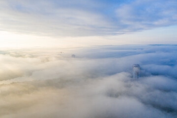 Obraz premium Photo from a height of a foggy city! Several buildings and a construction crane can be seen through the fog.