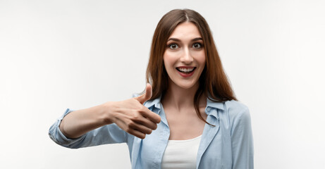 Happy Young female with long chestnut hair shows OKAY sign with both hands, demonstrates approval
