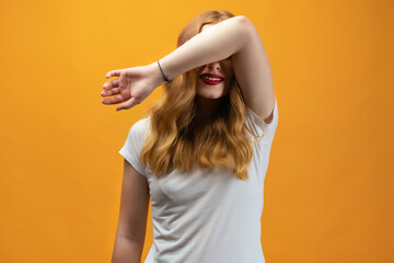 Young woman with long wavy blonde hair covers eyes with arm. Blind concept