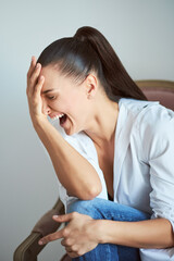 Fototapeta premium Laughing woman in armchair. Studio shot.