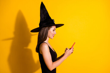 Profile side view portrait of her she attractive pretty focused addicted cheerful lady wizard using gadget app 5g comment feedback repost isolated bright vivid shine vibrant yellow color background