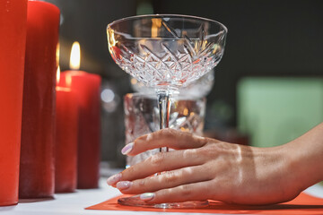 Woman's hand touch glasses on the table with candles. table setting