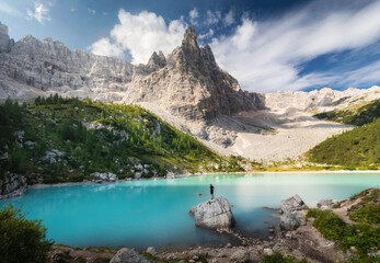 Amazing view of Sorapis lake (Lago di Sorapis) with man on the rock looking on the mountain Dolomites