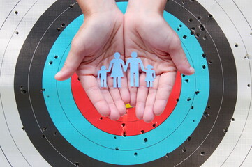Paper family in hands on archery target background