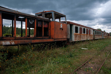 Fototapeta na wymiar Old rusty diesel locomotive with broken passenger cars on the railway