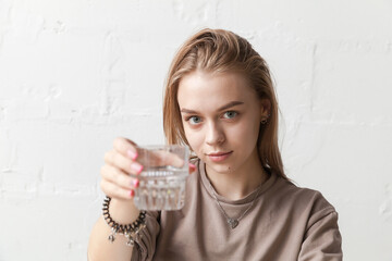 Young blond girl holds a glass of water, close-up