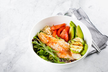 Healthy Salad Fish Bowl. Zander, vegetables, green leaves, avocado, tomato and brown rice in bowl.