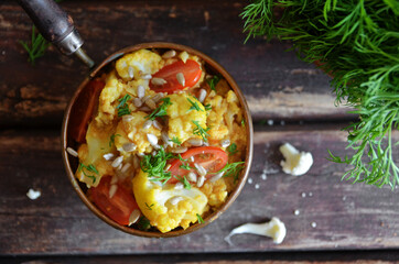 Cauliflower curry in rustic bowl on wooden background