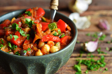 Vegetable stew in a green rustic bowl on a wooden background