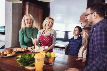 Three generation family in kitchen preparing lunch, having fun