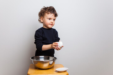 , the kid learns to wash his hands properly with soap. Hygiene rules and good habits. cute curly baby boy washes his hands with a dense soap bar on a white studio background.