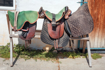 Harness for horses in horse club. Worn ranch saddles and girth. Ridding school on a horse farm