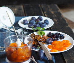 Process stage of making juice or smoothie from blue ripe plum. Mixer with plum and ingredients on a dark background.