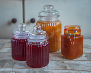 A set of jars with homemade jam on a room table, red currant and apple jam