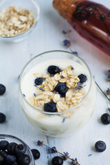 Homemade yogurt in a glass with lavender and blueberry on white  wooden background. Top view.