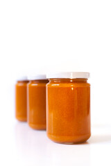 Selbstgemachte Aprikosen-Konfitüre im Glas vor weißem Hintergrund. Marillenmarmelade selbst gemacht. Homemade apricot jam. Homemade apricot jam in a glass against a white background. 