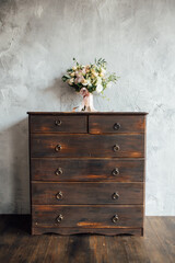 wedding bouquet on dresser near gray wall with vintage texture