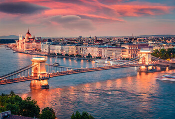 Fototapeta na wymiar Breathtaking evening view of Parliament and Chain Bridge in Pest city. Amazing spring cityscape of Budapest. Stunning sunset in capital of Hungary, Europe. Traveling concept background..