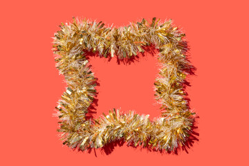 golden tinsel frame on a coral red background