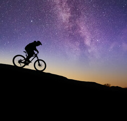 Cyclist Riding the Bike on the Rock Under the Night Sky. Sport Lifestyle and Adventure Concept.