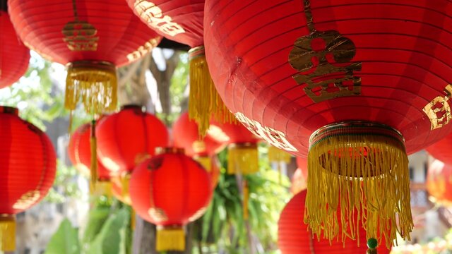 Paper lanterns on shabby building. Red paper lanterns hanging on ceiling of weathered concrete temple building on sunny day in oriental country. traditional decoration