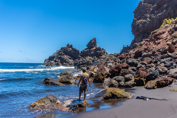 A young tourist enjoying summer by the sea on some rocks in Playa de Nogales in the east of the Island of La Plama, Canary Islands. Spain