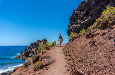 A young woman walking along the path in summer to the beach of Nogales in the east of the Island of La Plama, Canary Islands. Spain