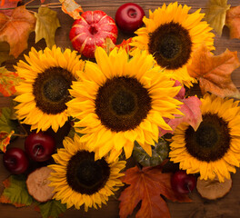 Sunflowers, dried leaves, pumpkins, apples and rowan berries on rustic wooden background. Autumn, fall, thanksgiving day concept.