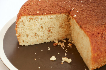 Homemade teacake on a brown plate with cut out pieces isolated on white background. Concept of home made cakes and sweet food made at home