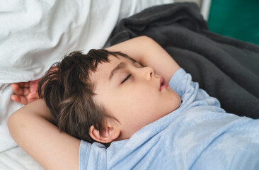 Fototapeta na wymiar Adorable kid deep sleep in bed in the morning, Child sleeping on bed. Little boy taking a peaceful nap, Children health care concept