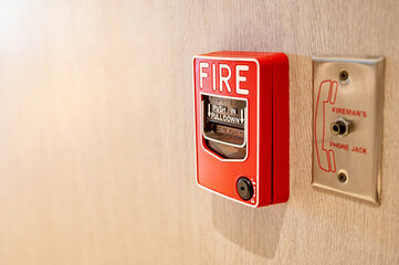 Red fire alarm switch and phone jack for fireman on wooden wall in office building. Industrial fire...