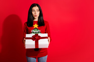 Fototapeta premium Portrait of her she nice attractive lovely pretty amazed winsome girl holding in hand festal giftbox pout lips looking aside copy space advert isolated bright vivid shine vibrant red color background
