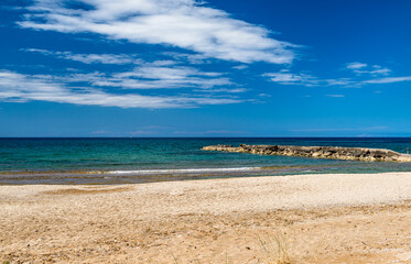 Seascape, deserted sandy beach, green sea and blue sky.