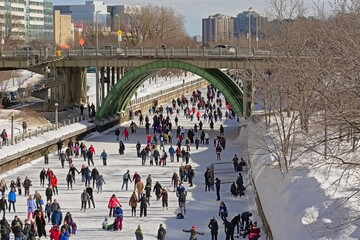 Many people ice skating on the frozen rideau canal on a cold winter day during the winterlude...
