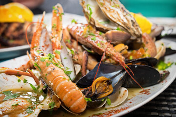 Delicious seafood platter from Malta  - freshly caught and grilled octopus tentacles, calamari rings in tempura, giant shrimps, clams, fish fillets and mussels 