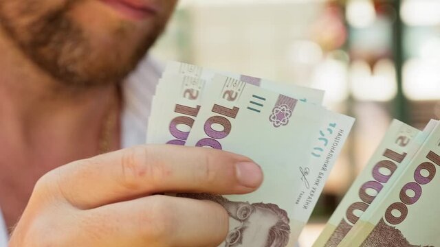 Cinematic shot: Men's hands consider Ukrainian money with a nominal value of one thousand hryvnias. Person counts banknotes. Man counts a large wad of money. Human hands with money
