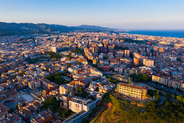 Aerial panoramic view of Sant Adria de Besos and Badalona with Mediterranean sea and Sierra de la Marina mountains in background on sunny day, Spain