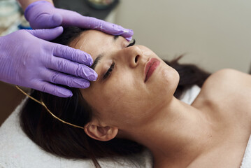 Young woman having anti-stress facial massage in salon at spa resort. Face massage. Facial skin care. Woman at beauty spa salon