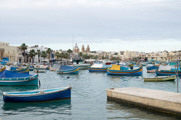 Fototapeta na wymiar The traditional maltese luzzu boats in the harbor of fishing village Marsaxlokk in Malta 