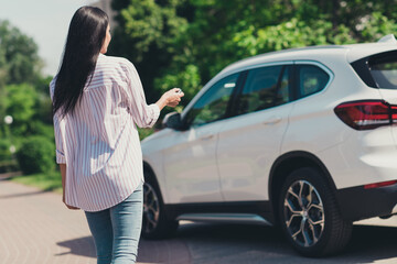 Back rear spine view photo of girl new car owner go walk auto open door remote keys press button in...