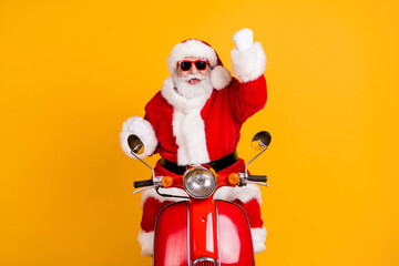 Fototapeta na wymiar Portrait of his he nice cool cheerful cheery lucky Santa riding moped celebrating rejoicing accomplishment isolated bright vivid shine vibrant yellow color background