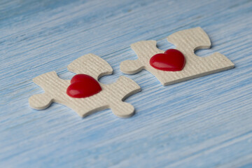  idea that love is a matter of two. Puzzles with the two red  hearts on a blue wooden background.