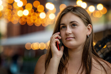 young woman talking on mobile phone on street night with light bokeh background