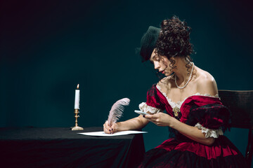 Texting. Young woman as Anna Karenina isolated on dark blue background. Retro style, comparison of eras concept. Beautiful female model like literature character, great, old-fashioned.
